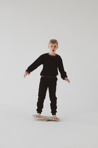 A BOY BALANCING ON THE GREY BALANCE BOARD / TRICK BOARD FOR KIDS- GOOD WOOD