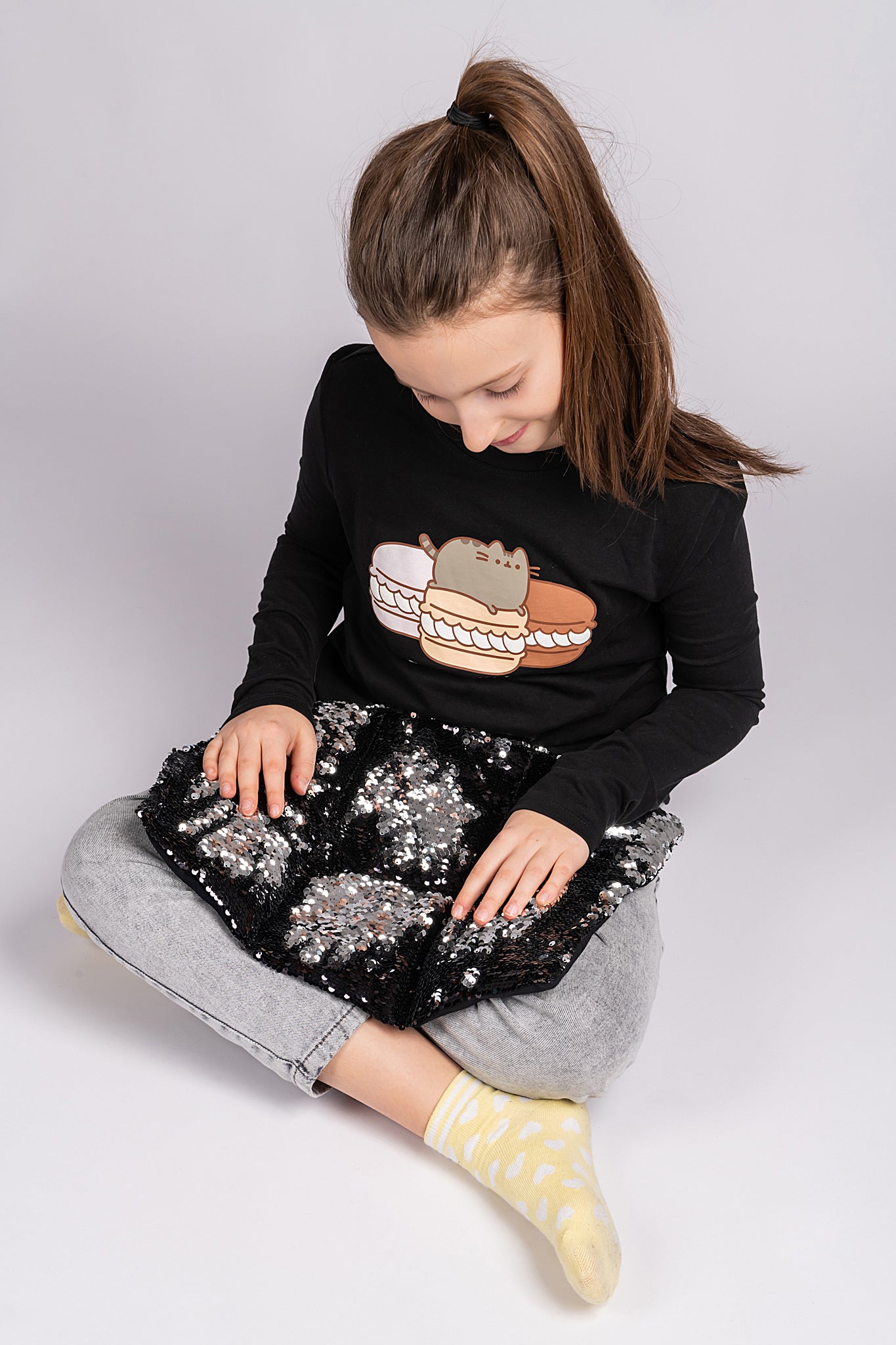 girl sitting with Two tone sequin weighted lap pillow in black and silver